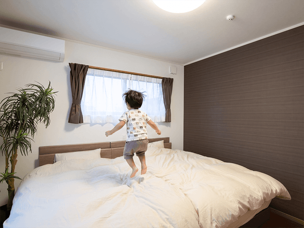 窓の近くのベッドで飛び跳ねる2歳児